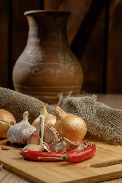 Oignons, chili et ail sur une table en bois . — Photo