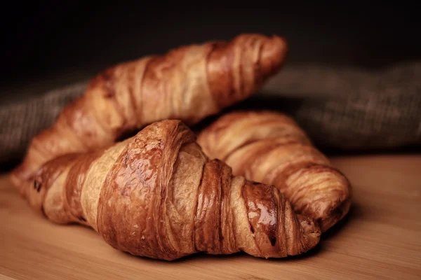 Ein paar frische Croissants auf einer Holzoberfläche — Stockfoto