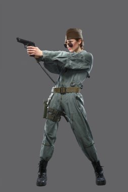Elinde bir tabanca ile bir helikopter pilotu kılığında bir kız.