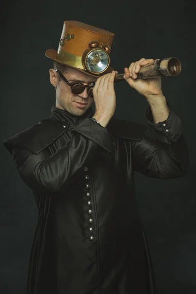 Hombre Steampunk en un abrigo largo mirando a través de un telescopio . —  Fotos de Stock