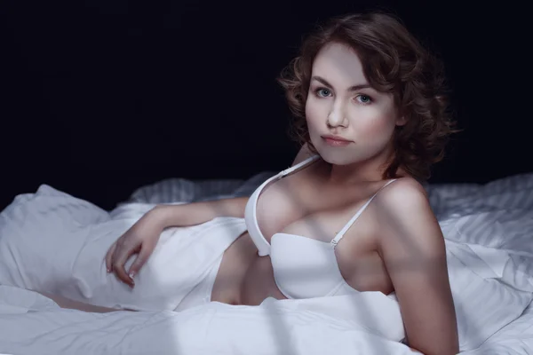 Sexy brunette in bed. Maanlicht vanuit het venster — Stockfoto