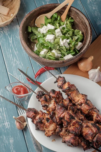 Shashlik com salada na mesa de madeira . — Fotografia de Stock