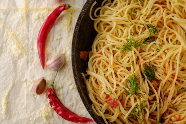 Spaghetti Pasta in airon frying pan with garlic, tomatoes and sp — Stock Photo, Image