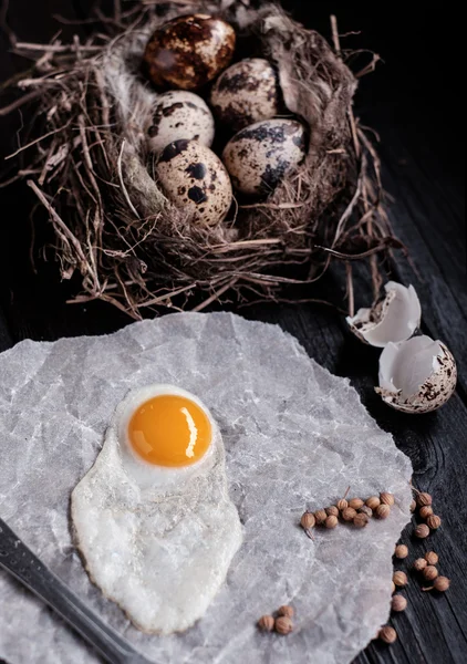 Uova di quaglia nel nido e un uovo fritto su una tavola di legno . — Foto Stock