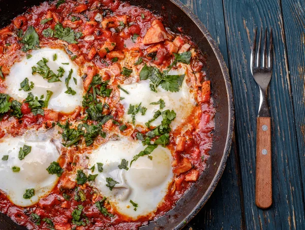 Смажені яйця на сковороді з помідорами, ковбасою та зеленню — стокове фото