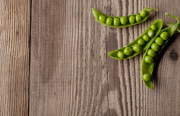 Guisantes verdes maduros en mesa de madera . — Foto de Stock