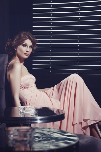 Glamorous woman in a pink dress sits at restaurant table. — Stock Photo, Image