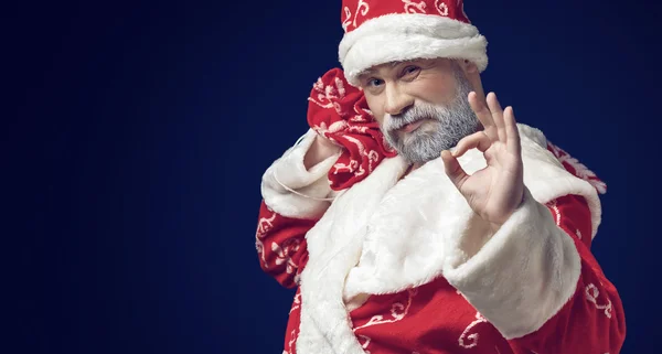 Weihnachtsmann zeigt Ok-Zeichen auf blauem Hintergrund — Stockfoto