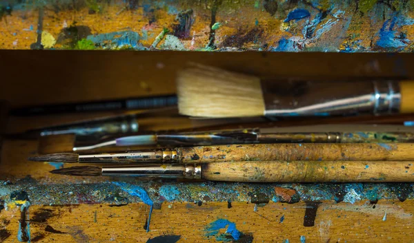 Kunstenaar verfborstels close-up op oude houten ezel — Stockfoto