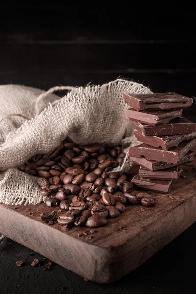 Frisch geröstete Kaffeebohnen und ein Stapel brauner Schokolade. — Stockfoto