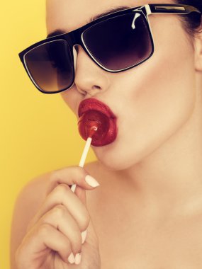 Beautiful amazing sexy smiling woman in sunglasses with a lollip