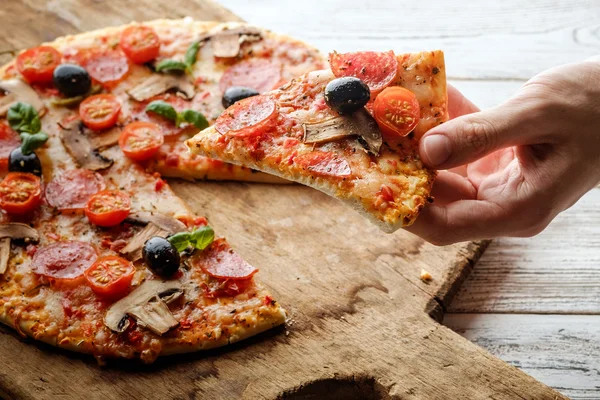 Mannenhand plukken smakelijke pizza slice. — Stockfoto