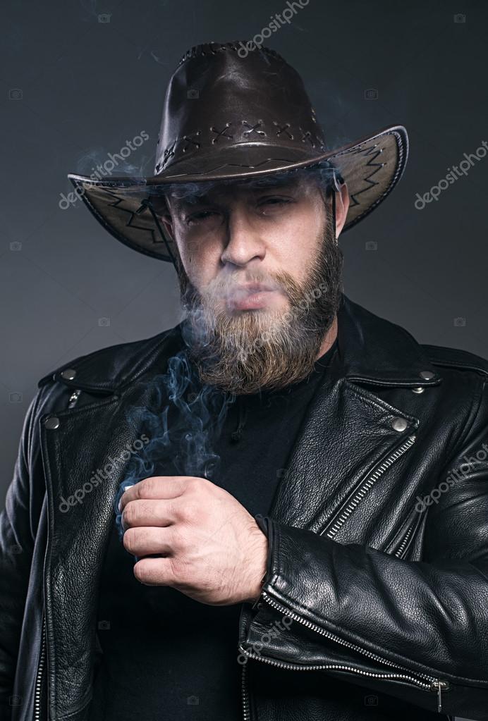 Smoking man with a beard and mustache wearing a cowboy hat