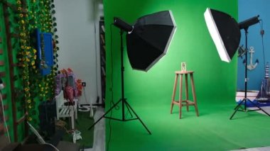 Altı köşeli stüdyo ışıkları olan fotoğraf ya da video stüdyosu. Yeşil perdede kum saati ve sabitlenmiş sandalye