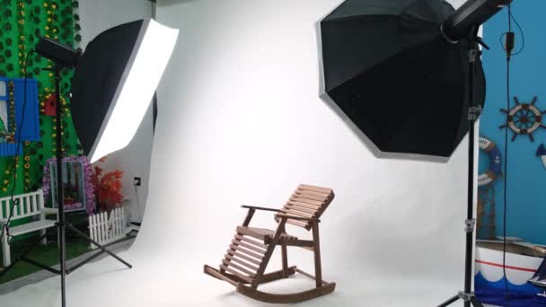 Foto- oder Videostudio mit zwei sechseckigen Studioleuchten. Weiße Leinwand und Schaukelstuhl — Stockvideo