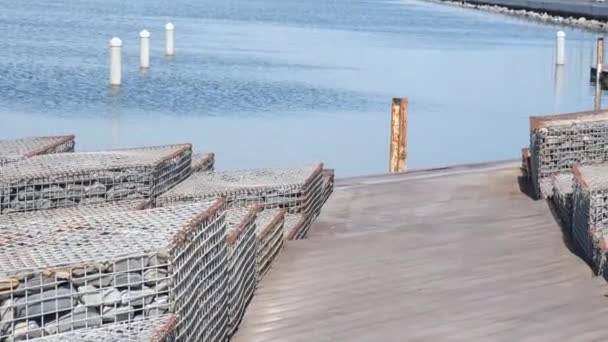 Piedras decorativas en jaula cableada en la costa de lago artificial. Disparo estático de mano. Vídeo 4k — Vídeos de Stock