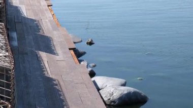 Gölün ahşap kıyıları insanların dinlenmesi için yapılmıştır. Dalgalı su yüzeyi. Statik el kamerası atışı. 4k Video