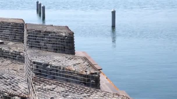 Kamienie dekoracyjne w klatce przewodowej na wybrzeżu sztucznego jeziora. Ręczny strzał statyczny. 4k wideo — Wideo stockowe