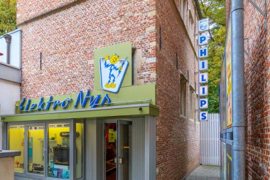 Genk, Belçika. 17 Ekim 2025. 1960 'ların teçhizat mağazası, aydınlatılmış dükkan penceresi ve ön cephede ve duvarda asılı reklam, Bokrijk Açık Hava Müzesi' nin dar geçidi.