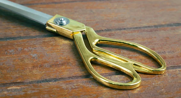 Gouden schaar op een houten werktafel — Stockfoto