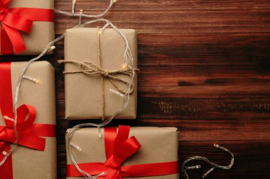 Noel ve yeni yıl hediye kutularıyla ve tahta masa arkaplanındaki sicim ışığı dekorasyonuyla fotokopi alanı ile birlikte..