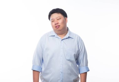 Mavi gömlekli Asyalı şişman adam beyaz arka planda izole edilmiş kameraya bakıyor..