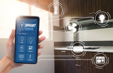 Akıllı ev teknolojisi kavramı, uygulama simgeleri, internet (IOT), ev içlerine bağlı aygıtlar ile kontrol edilen mutfak için akıllı telefon uygulaması kullanan kadın eli.