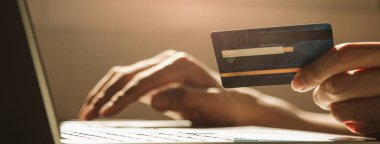 Bilgisayarı kullanan ve online alışveriş, e-ticaret, internet bankacılığı, fotokopi alanı olan Panoramik web pankartı için çalışan masasında kredi kartı tutan eller.