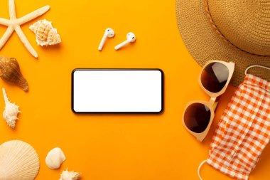 Boş ekran telefonlu ve plaj aksesuarlı yaz arkaplanı, canlı turuncu arkaplan görünümlü covid-19 'un fotokopi alanı ile görüntülenmesini önlemek için maske.