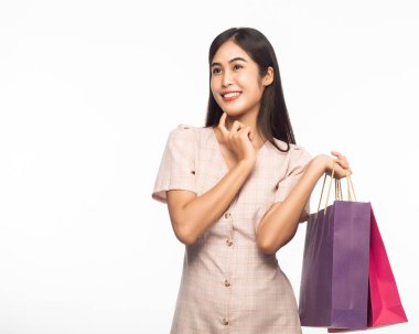 Heyecanlı, güzel Asyalı bir kadının portresi. Elbise giyiyor ve beyaz arka planda izole edilmiş alışveriş torbaları tutuyor..