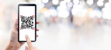 Alışveriş merkezinin afiş arka planında cep telefonu tarayıcı QR kodu kullanılıyor. Barkod okuyucu, Qr kod ödemesi, Nakitsiz teknoloji, Dijital para kavramı.