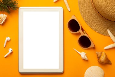 Boş tablet bilgisayar ve plaj aksesuarları ile yaz arkaplanı - güneş gözlüğü, parlak turuncu arka plan görünümlü hasır şapka fotokopi alanı ile.