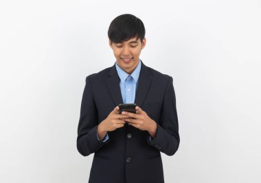 Yakışıklı Asyalı iş adamı beyaz arka planda sırıtan akıllı telefon kullanıyor..