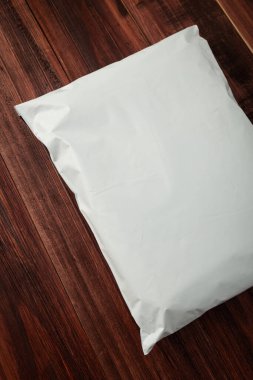 Tahta arka planda boş beyaz plastik poşet modelleme, çevrimiçi alışveriş paketleme, paketleme şablonu.