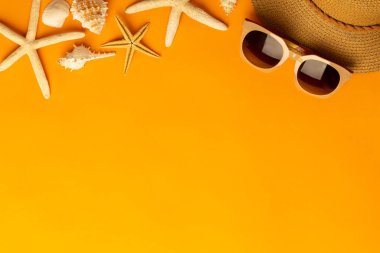 Plaj aksesuarlarıyla yaz arkaplanı - hasır şapka, parlak turuncu arka plan manzaralı güneş gözlüğü.