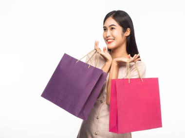 Heyecanlı, güzel Asyalı bir kadının portresi. Elbise giyiyor ve beyaz arka planda izole edilmiş alışveriş torbaları tutuyor..