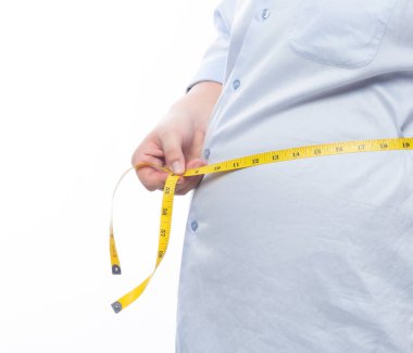 Şişman adam, beyaz arka planda izole edilmiş vücudunu kontrol etmek için bir mezura tutuyor..