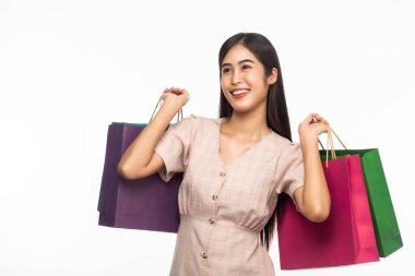 Heyecanlı, güzel Asyalı bir kadının portresi. Elbise giyiyor ve beyaz arka planda izole edilmiş alışveriş torbaları tutuyor..