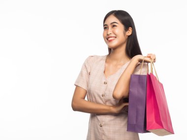 Heyecanlı, güzel Asyalı bir kadının portresi. Elbise giyiyor ve beyaz arka planda izole edilmiş alışveriş torbaları tutuyor..