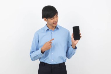 Genç Asyalı yakışıklı iş adamı beyaz arka planda boş ekranlı akıllı telefon gösteriyor ve gülümsüyor..