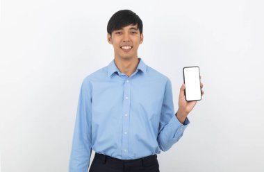 Genç Asyalı yakışıklı iş adamı beyaz arka planda boş ekranlı akıllı telefon gösteriyor ve gülümsüyor..