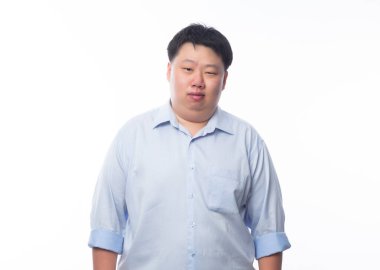 Mavi gömlekli Asyalı şişman adam beyaz arka planda izole edilmiş kameraya bakıyor..