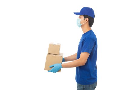 Maske takan ve eldiven takan genç teslimatçı elinde karton kutu ile beyaz arka planda izole edilmiş kırpma yolu ile izole edilmiş karton kutu tutuyor..