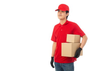Kırmızı üniformalı genç teslimatçı elinde karton kutuyla beyaz arka planda kırpma yolu ile izole edilmiş..
