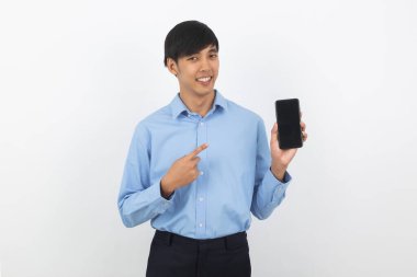Genç Asyalı yakışıklı iş adamı beyaz arka planda boş ekranlı akıllı telefon gösteriyor ve gülümsüyor..
