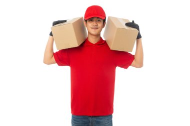 Kırmızı üniformalı genç teslimatçı elinde karton kutuyla beyaz arka planda kırpma yolu ile izole edilmiş..