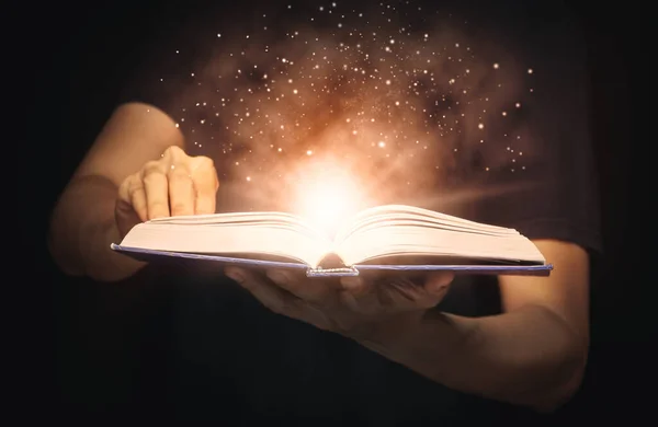 Büyüyen ışıklar ve sihirli tozla adam sihirli bir kitap açtı. Öğrenim ve eğitim kavramı.