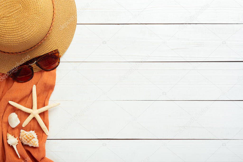 Summer background with beach accessories - straw hat, sunglasses, towel on white wood table background top view with copy space.