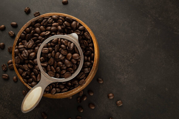 Coffee beans in wooden bowl on grunge background.