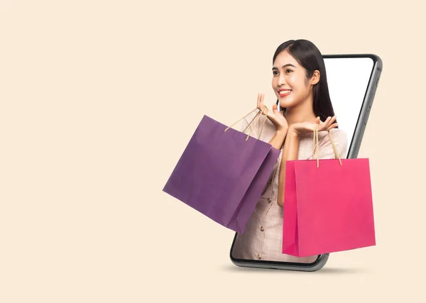 年轻的 面带微笑的 美丽的亚洲女人正在网上购物 并通过手机把购物袋拿出来 这些都是在米色背景下与剪贴路径隔离的 — 图库照片